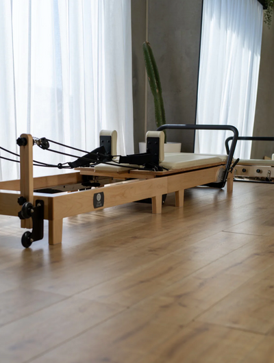 Side view of a foldable Pilates reformer showcasing its durable frame, cushioned padding, and smooth glide system for home workouts.